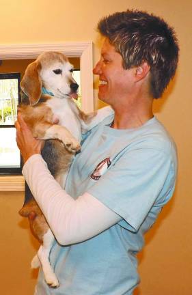 Canine Country Club of the Lake owner-operator Jodi Brooks holding Makena, an eight-year-old purebred beagle and guest at the facility