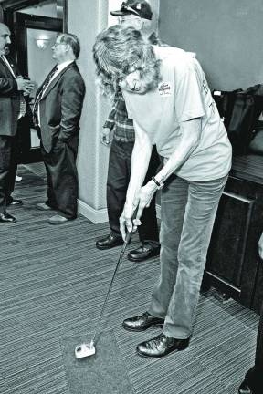 Sussex County chamber hosts business expo Christa Gerry of Vernon tries her hand at putting for prizes at the Nation Life Group insurance company booth.