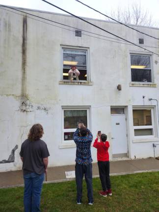 Cara McLaughlin, youth services associate at the Franklin library branch, drops three entries in the Egg Drop Challenge out the second-story window Saturday, March 25. (Photos by Ava Lamorte)