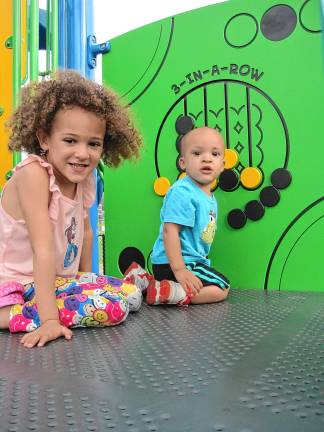 Inclusive playground opens Anna Leah Burke, 5, and her brother Malachi, 1, playing 3-in-a-row. (Photo by Theresa Esposito)