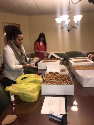 In the Project Self-Sufficiency board room, Michelle Michaluk and Vanessa Portante prepare goody bags. Their children are two of the young volunteers. (Photo by Laurie Gordon).