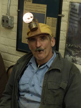 Chipping away for treasure Thomas Hauck, property manager of the Sterling Hill Mining Museum modeling a restored mining hat lamp. The bright acetylene flame is produced by water dripping onto carbide chips inside the body of the lamp. Hauck said the lamp was preferred by older miners as they could light dynamite fuses and their cigarettes with the open flame.