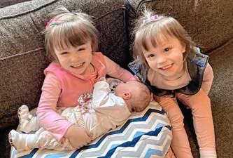 Identical twins Rebekah and Charlotte Smith hold their sister, Sadie, who was born Feb. 29. (Photos provided)
