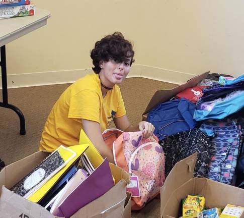 Aileen Itter sorts new backpacks donated to Project Self-Sufficiency (PSS) for distribution to needy children.(Photo courtesy of PSS)