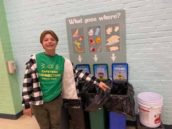 Ayden Degan points to a recycling bin.