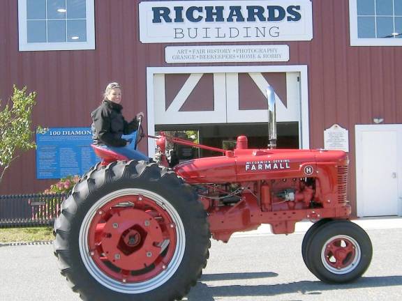 A tractor operator is all smiles as she joins the tractor parade at Rooster’s Day at the Fair at the Sussex County Fairgrounds in Augusta (Photo by Redyke)