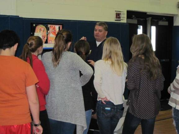 From baseball to microbiology Rick Fahey demonstrates virtual-reality surgery at Career Day in Stanhope, while seventh and eighth-grade students look on.