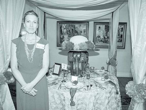 A Taste of Talent Project Self-Sufficiency case manager Linda Moran stands next to the table display she designed.