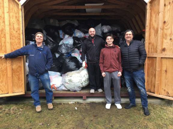 Clothes donations help high school band Lenape Valley Regional High School Marching Band Shed – filled with clothing donations from Clean Out for a Cause. Pictured, from left: Michael Bender of Millennium Textile; David DiGrazia, LVRHS Band Director; Matthew Maiello, LVRHS Band Student; and Jake Stigers, LVRHS Band Parent.
