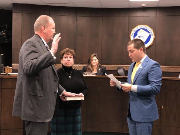 Michael Carlucci, left, takes the oath of office as the new municipal judge in Newton. Holding the Bible is his wife, Alice Collopy.