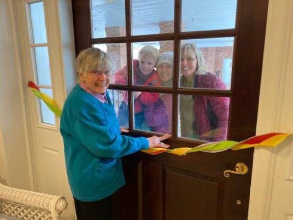 A resident at The Chelsea at Bald Eagle visits with loved ones via telephone through the door.