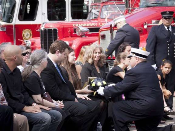 Photos by Glynnis Jones Byram Twp Fire Department President Larry Putz presents Richard Choate's fire helmet to Casey O'Connell Choate during the LODD Ceremony for her father, Byram Twp Firefighter Richard Choate.