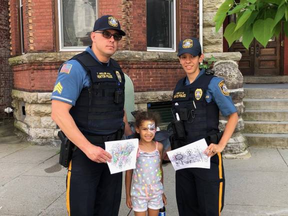 Community bonding A little girl gives pictures she colored to Newton Police Sgt. Muller and Newton Police Officer Torres at Newton Day. (Photo provided)