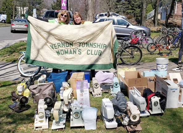 International Committee chair Karen Rothstadt (left) and communications chair Lisa Mills display their club banner with many of the 58 sewing machines collected during the 2019 project (Photo provided)