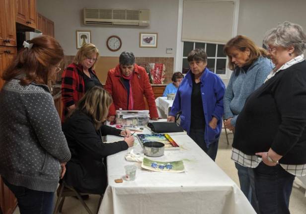Class members gather around artist Toni Chaplin as she demonstrates painting technique in Art class in Sparta on Thursday, Nov. 7, 2019. The class members say they have found that the weekly lessons bring camaraderie, good humor, and excellent teaching.