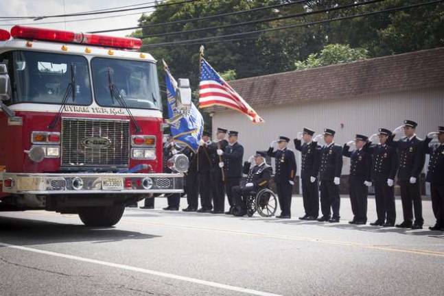 Firefighters from the Byram Fire Dept line Route 206 in front of the fire house as the procession of fire trucks pass by during the LODD Ceremony for FF Richard Choate.