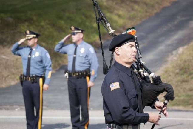 Bagpiper FF John Bradley from the Clifton FD walks past Byram police officers as he plays at the end of the LODD Ceremony for Byram Twp Firefighter Richard Choate.