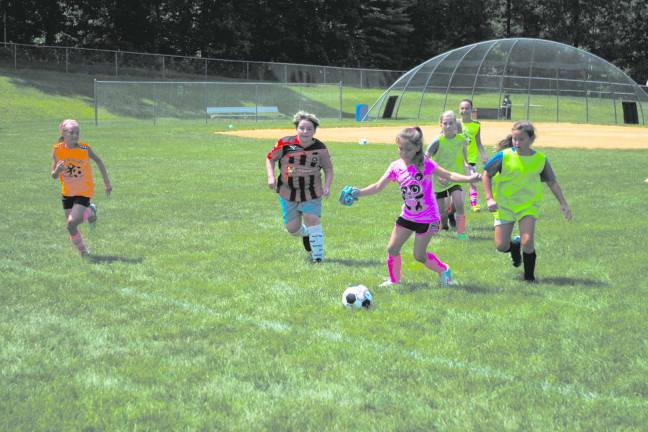 Youngsters learn soccer fundamentals during camp Girls in action on the field.