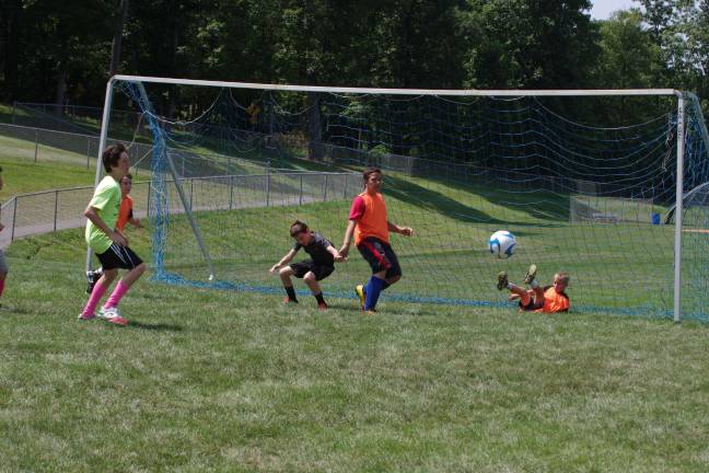 Youngsters learn soccer fundamentals during camp Action in front of the goal post.