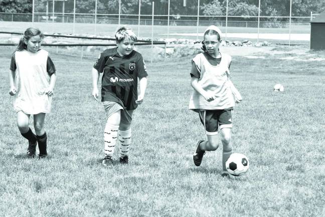 Youngsters learn soccer fundamentals during camp Eleven-year-old Madeleine Schuman drives the ball.