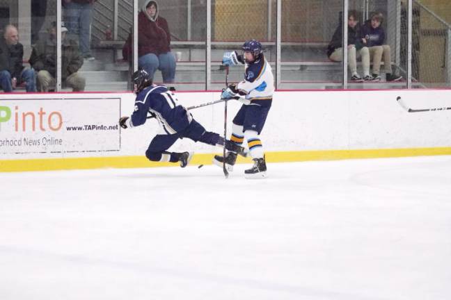 A Roxbury Gael begins to fall while pursuing the puck and clashing with a Sparta-Jefferson United player.