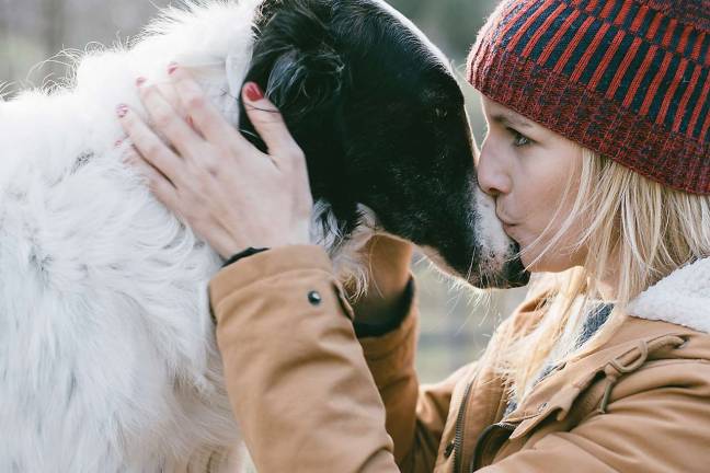Beautiful woman kissing her dog outdoors. Girl with her dog. Cute dog loves her owner.