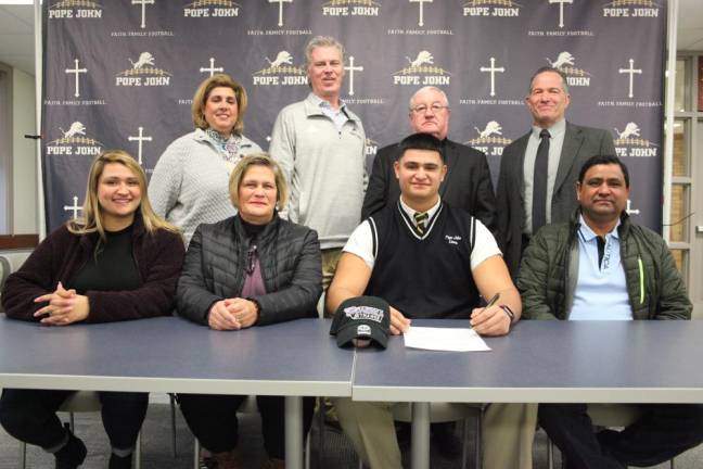 Pope John senior Sebastian Flamenco signs his National Letter of Intent to continue his academic and football careers at Stonehill College. Seated next to Flamenco, from left, are his sister, Jennifer, his mother, Heidi, and father, Jubal.
