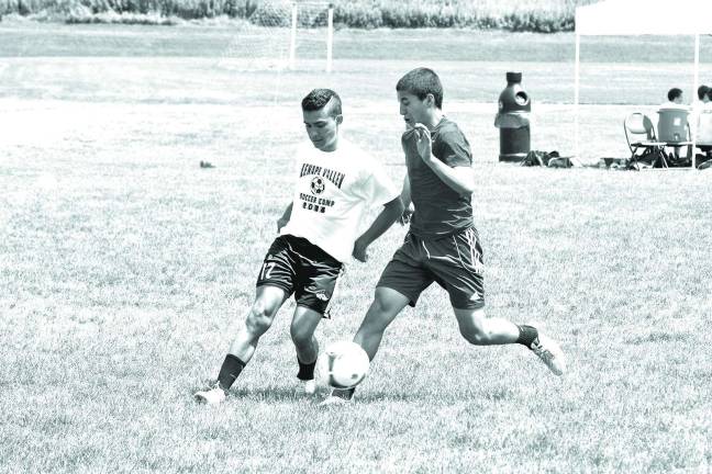 Youngsters learn soccer fundamentals during camp Two camp participants battle for the ball.