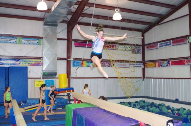 Skills clinic readies gymnasts Kayla Walton (17) leaps above the balance beam.