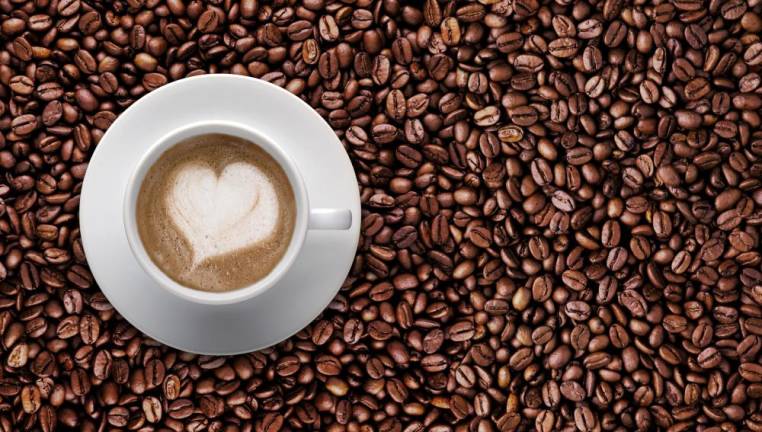 Meeting the Morning After Top view - Coffee cup of LATTE ART Love symbol lover sign on top Pile of brown coffee beans with copy space for text or graphic design. Cafe' latte cream on top coffee in heart shape on background of raw coffee beans
