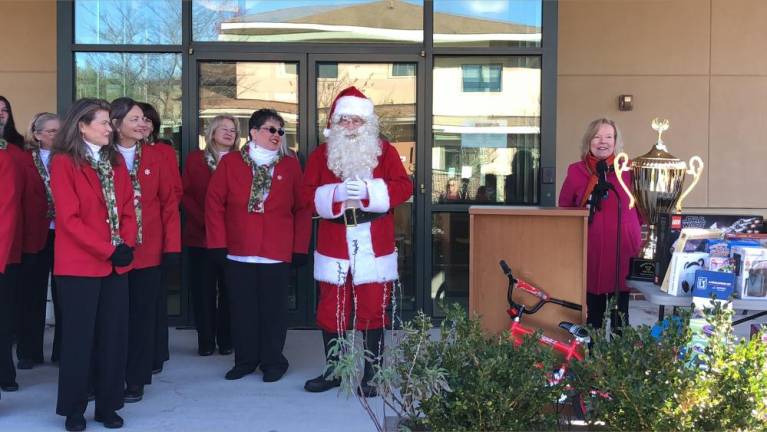 At right, Deborah Berry-Toon, executive director of Project Self-Sufficiency, stands near the big trophy that will go to the school that collects the most toys..