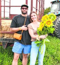 Francis Drake and Kimberly Osolin of Flanders pose with sunflowers.