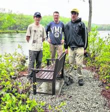 Life Scout Trey Hydock is shown with Assistant Scoutmasters Russ Raffay and James Braun in front of new bench with a view of Johnson Pond