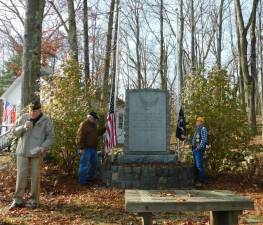 Caption: (L-R) Former Byram mayor, magistrate, and Army veteran Richard Bowe speaks at the Byram Veterans' Monument as Army veteran Paul Gryzwacz and Navy veteran Earl Riley prepare to raise the colors on Monday, Nov 11, 2019.