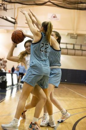 Pope John's Kylie Squier, with the ball, struggles to pass it while Sparta's Bailey Chapman (22) and another player block her.