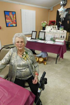 Florence &quot;Flossie&quot; Meyer poses in front of a table displaying her many achievements and accolades during a 100th Birthday Party in her honor on Saturday, Jan. 19, 2019, at the Walter Lynch Senior Center in Sparta. Playing under the table is the youngest party-goer, Meyer's 3-year-old great-grandson Gavin Healey DeMado.&#xa0;(Photos by Mandy Coriston).