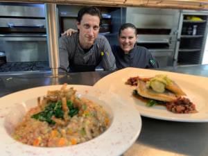 Mohawk House executive chef Peter Case and sous chef Mary Monteforte serving up two freshly prepared dishes: vegan farro risotto on the left, and mediterranean sea bass on the right. (Photo provided)