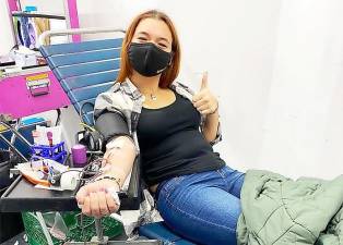 A blood donor gives a thumbs up to the cause.