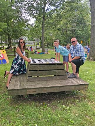 Stanhope Councilman Scott Wachterhauser; his wife, Jenn; and their son, Gavin, 9, play checkers on a big board.