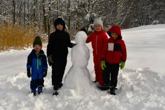SN1 Wesley Ledyard, left, and her brother Lucas, third from left, pose with Hunter and Sawyer Bruce and a snowman they made in their backyard in Sparta. (Photo by Maria Kovic)