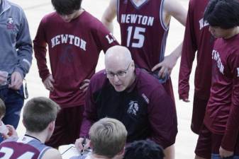 Newton High School head basketball coach Dirk Kelly discusses strategy with players during a break.