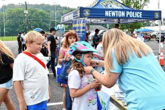 Rosalina Desibio has her bike helmet fitted during National Night Out on Tuesday, Aug. 5 in Newton. At left is Brentley Foutch. (Photos by Maria Kovic)