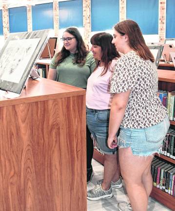 Sydney, Jennifer, and Charlotte Herold, all of Stanhope, look at art.