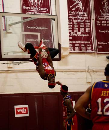 HW2 A Harlem Wizard player hangs upside-down from the basket during the game Thursday, Oct. 12 at Newton High School. (Photos by Nancy Madacsi)