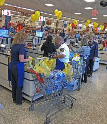 The local dignitaries and special guests bag quickly and carefully while chatting with ShopRite customers.