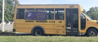 A Monroe-Woodbury school bus, parked outside of the bus garage on Mine Road in Monroe, carries a sign asking for new drivers. Photo by Hanna Wickes.