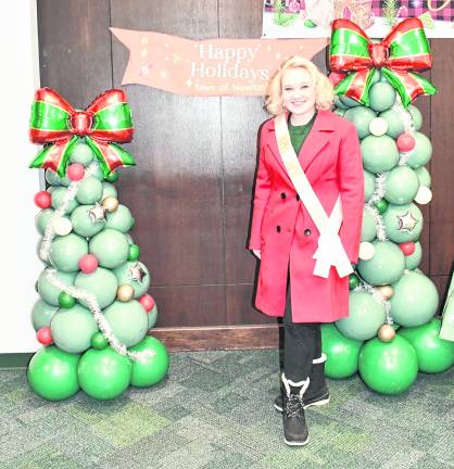 Miss Newton Danielle Penny stands in front of balloon Christmas trees.