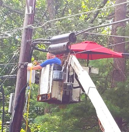 In an attempt to make Saturday's heat more bearable, a utility worker at the end of South Shore Trail in Sparta, brings an umbrella and a box fan up to his work site.&#xa0;(Photo by Shannon Kuratli).