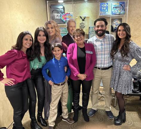 Carla Householder, center, and her family pose with cutouts of Pat Sajak and Vanna White at ABC Studios in California, where ‘Wheel of Fortune’ is taped. From left are her daughters Marissa DeVita and Mariel Cattani, grandson Anthony DeVita, son Joseph Householder and Emma Kramer, fiancée of her other son. (Photo provided)