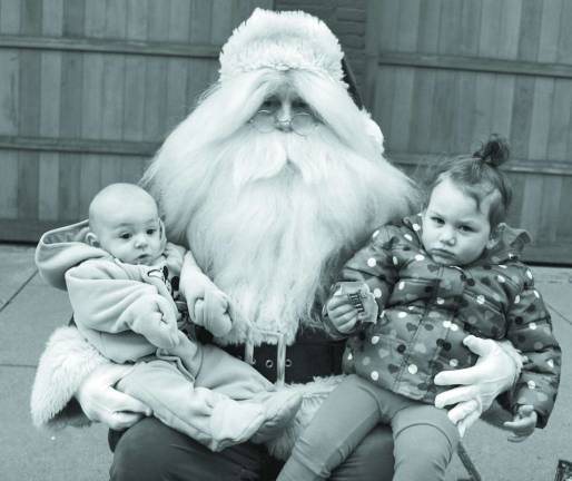 Siblings Kamren (4 months) and Kiana (2) Delgado of Newton, pose with Santa at the Newton Holiday Parade.